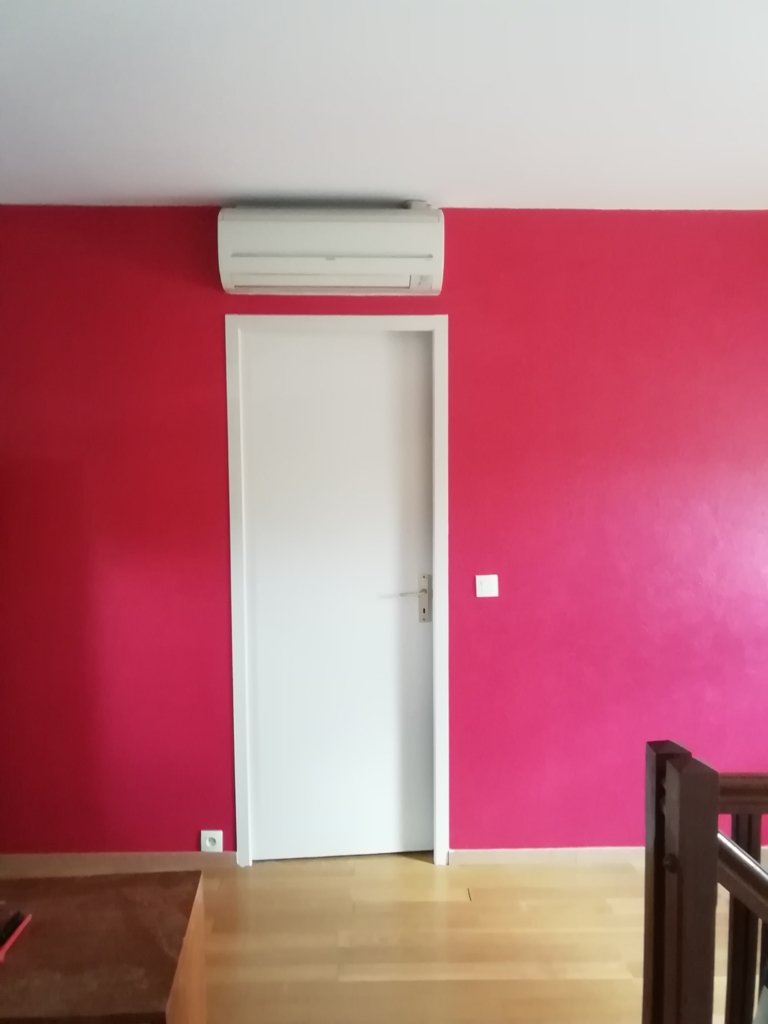 Mur peint en rose framboise autour d’une porte blanche