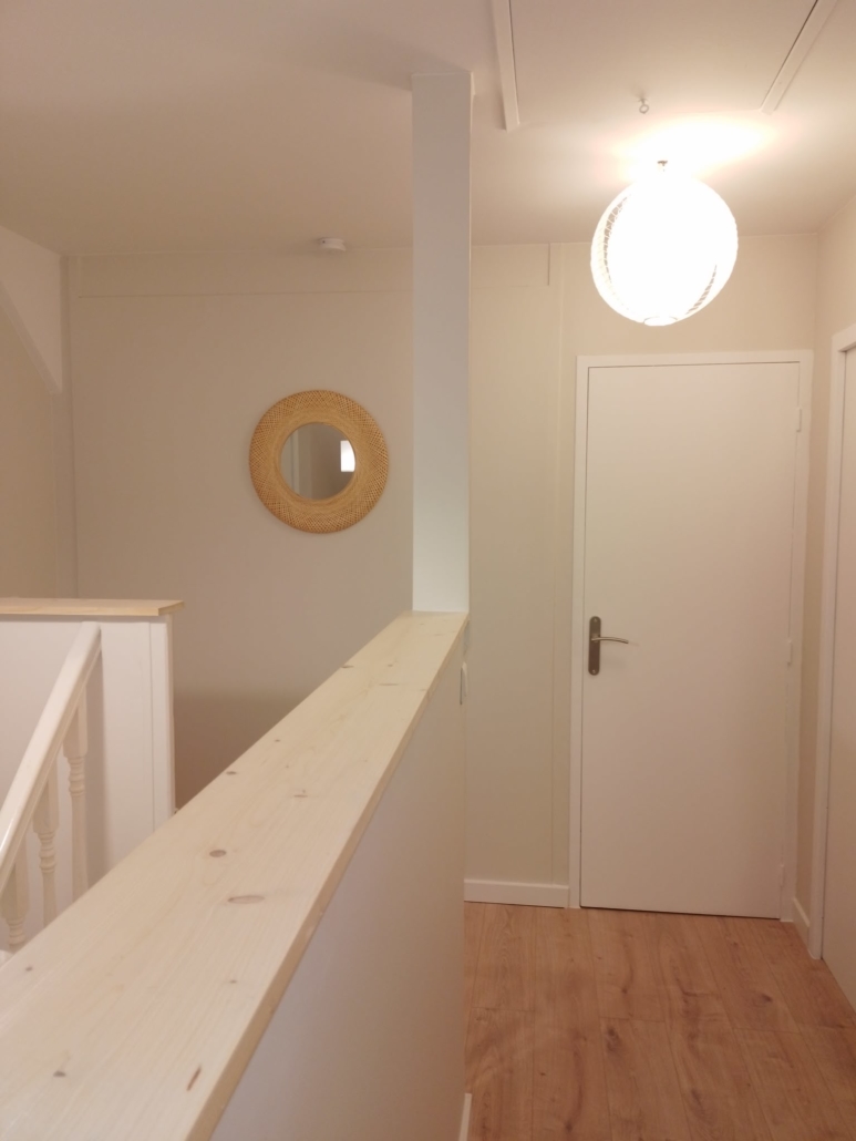 Palier aux murs blancs avec rambarde en bois clair