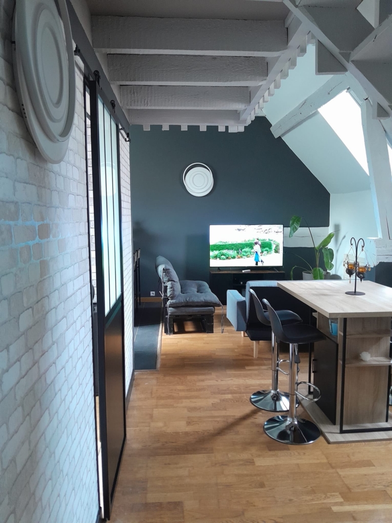 Séjour sous combles avec mur anthracite et poutres peintes en blanc