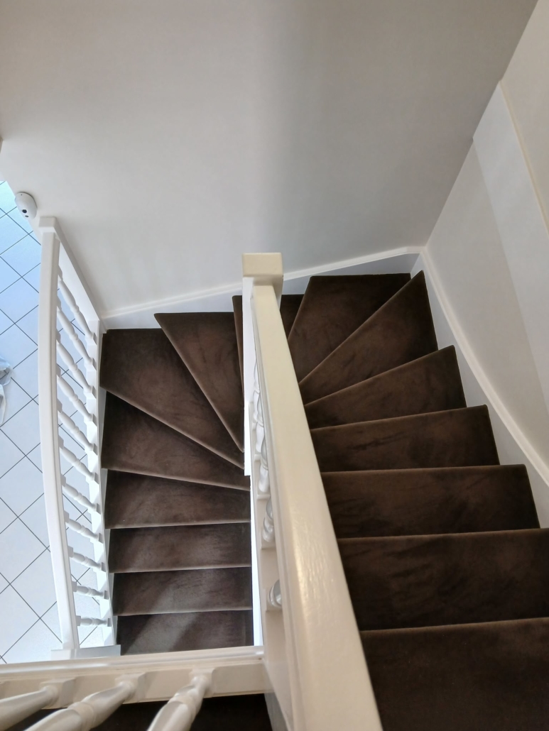 Vue plongeante sur une cage d’escalier aux murs et rampe blancs
