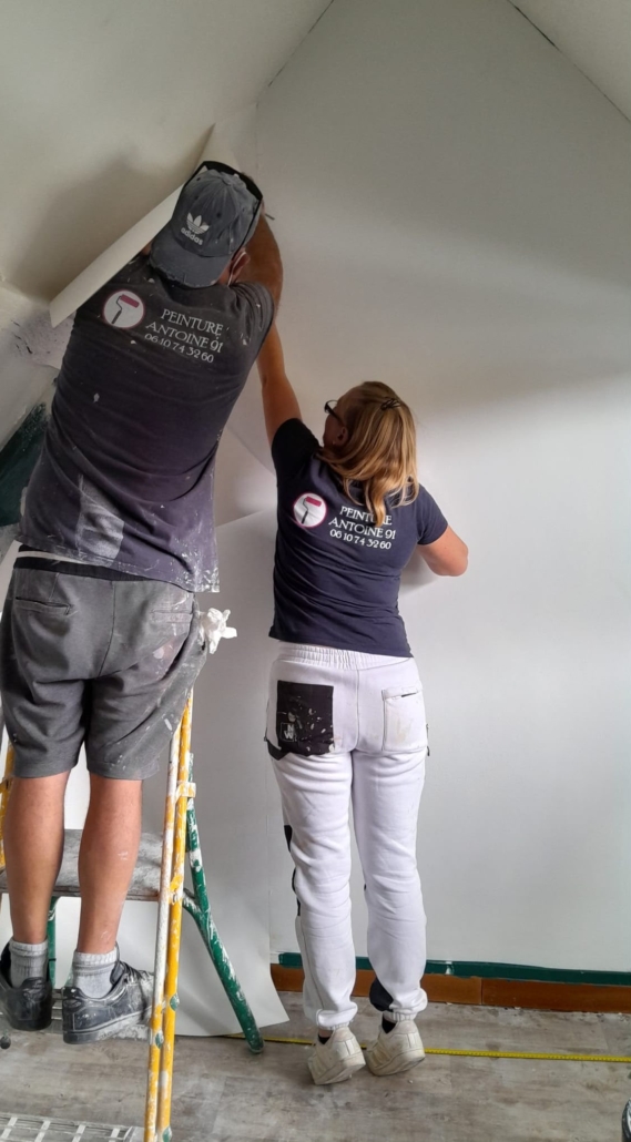 Xavier et Marion Antoine posant du papier peint sur un chantier